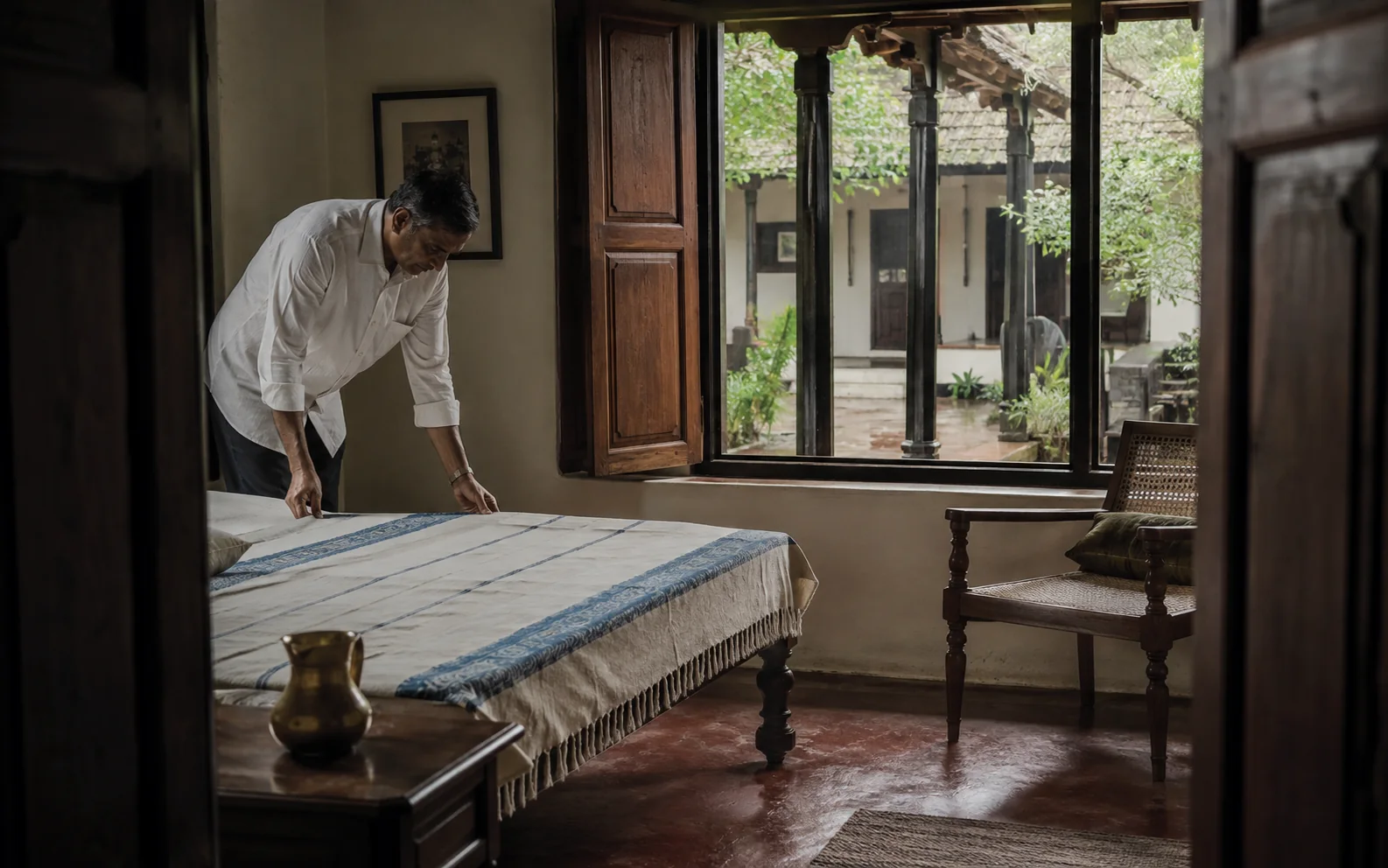 A caretaker preparing a bedroom in a restored South Indian home
