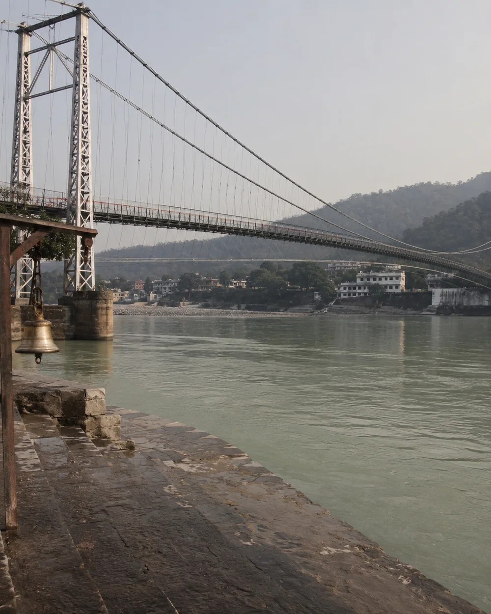 A suspension footbridge crossing the Ganga above stone steps in Rishikesh